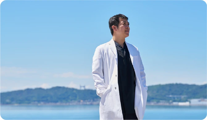 白衣のポケットに手を入れて立つ代表 胡谷俊樹